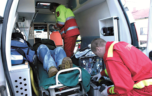 Kaksi ensihoitajaa hoivaa potilasta ambulanssissa.