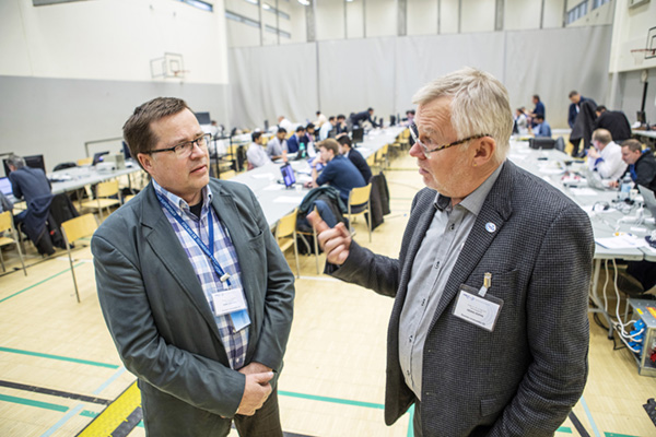 Plugtest-tapahtuman kokoussalissa Kari Junttila ja Heikki Riippa keskustelevat. 