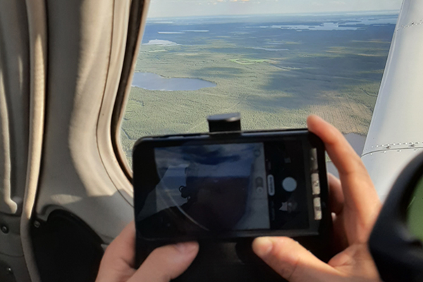 Videokamera kuvaa metsää lentokoneen ikkunasta.