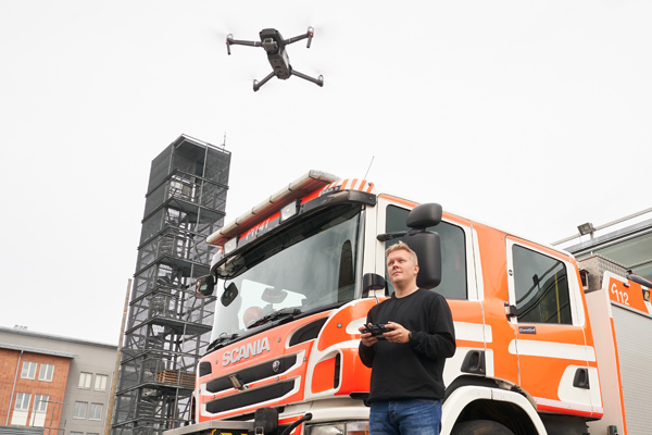 Mauri Kataja lennättää dronea paloauton vierellä. 